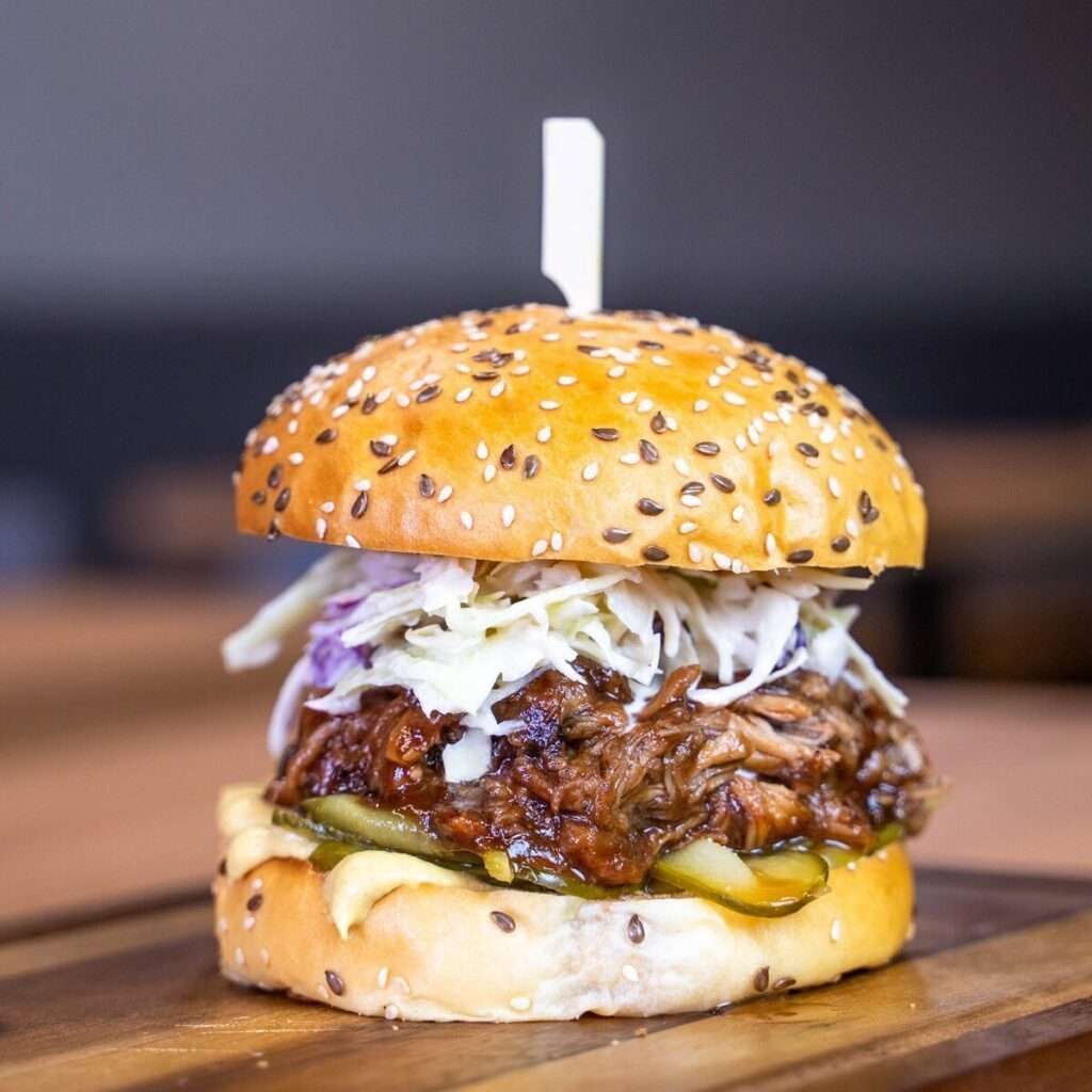 Pulled pork burger topped with coleslaw on a sesame bun