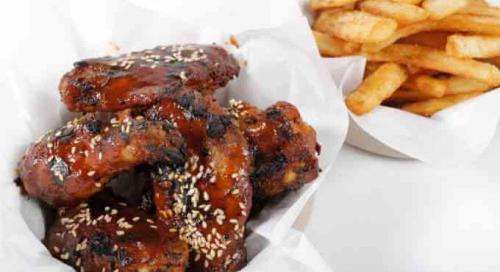 Slow-smoked BBQ chicken wings with sesame served with fries