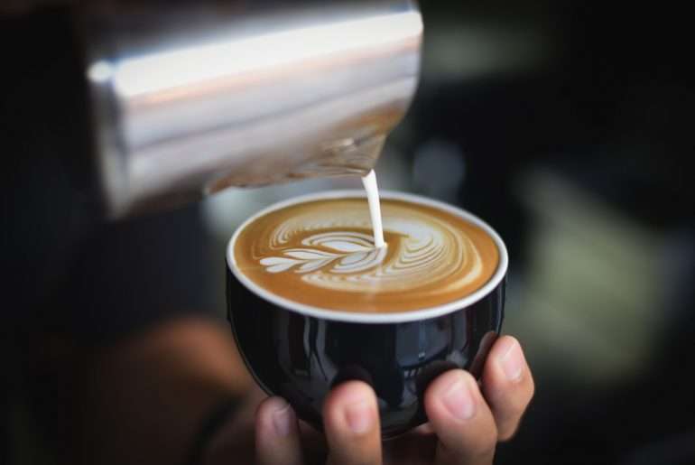 Barista pouring latte art into a coffee cup