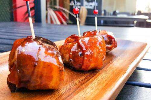 Three bacon-wrapped Oink Balls glazed in BBQ sauce on skewers