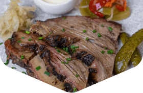 Sliced beef brisket with pickles and coleslaw on a plate