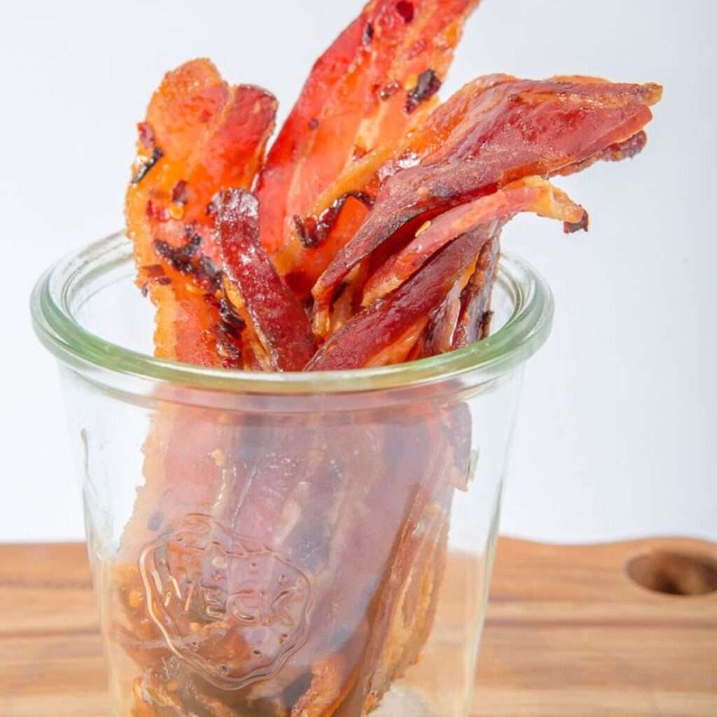 Candied bacon strips standing in a glass jar