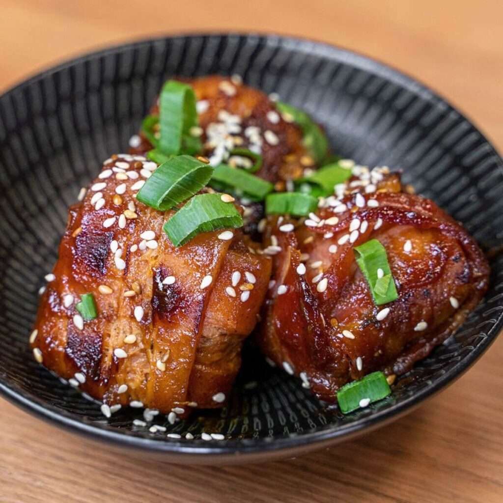 Two glazed Oink Ball pork bites topped with sesame and spring onion