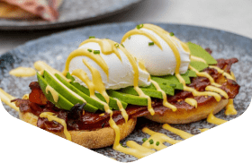 Poached eggs, avocado and bacon on toast with hollandaise drizzle