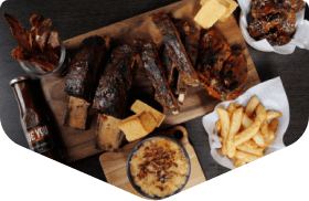 BBQ ribs platter with fries and dipping sauce on a wooden board