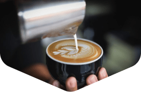 Hand holding a latte with leaf-pattern latte art