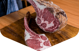 Raw bone-in steak cuts displayed on a wooden board