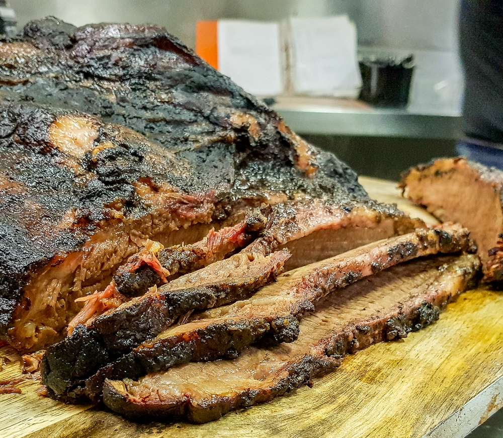 Sliced smoked beef brisket with a dark bark on a board