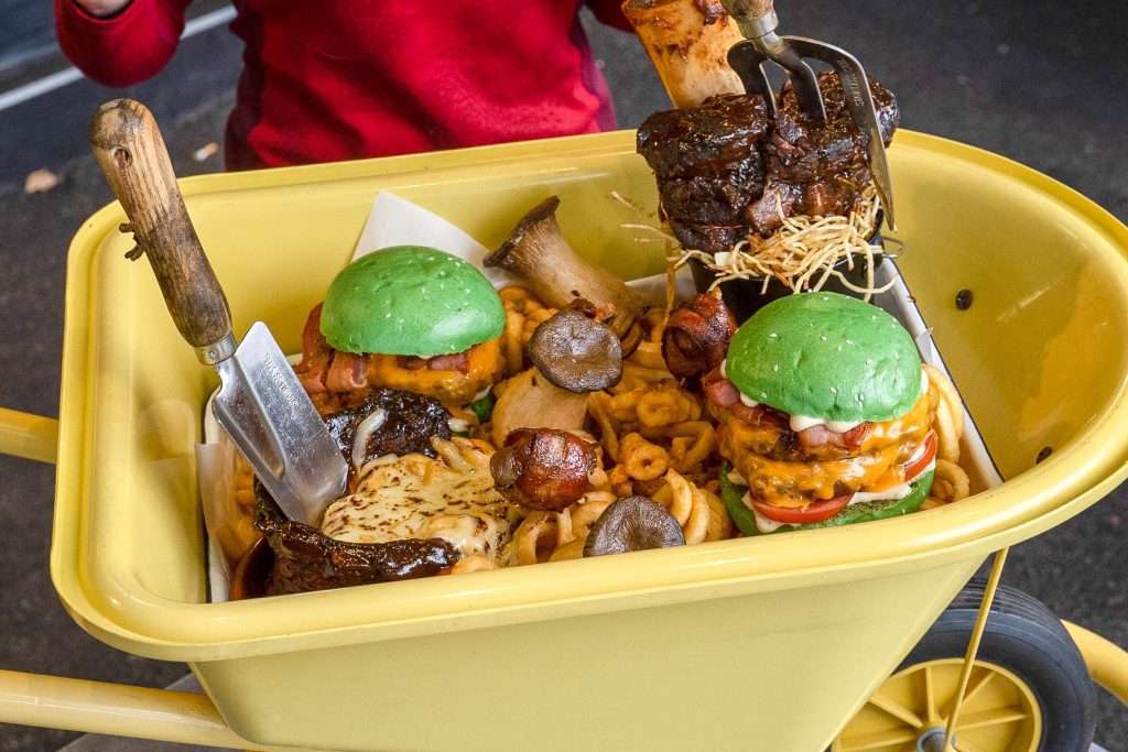 Wheelbarrow loaded with sliders, ribs, sausages and onion rings for a challenge