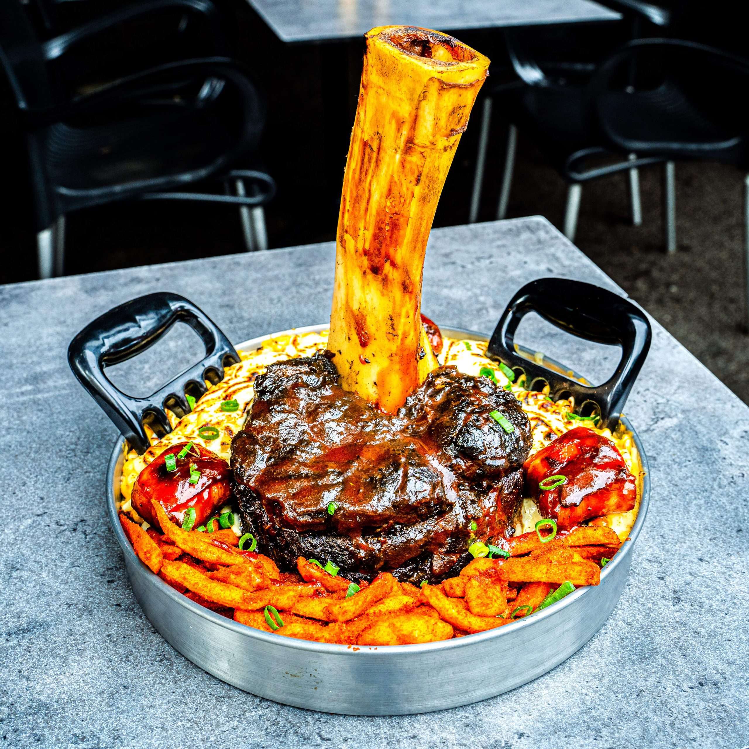 Thor's Hammer whole smoked beef shin standing in loaded cheesy fries