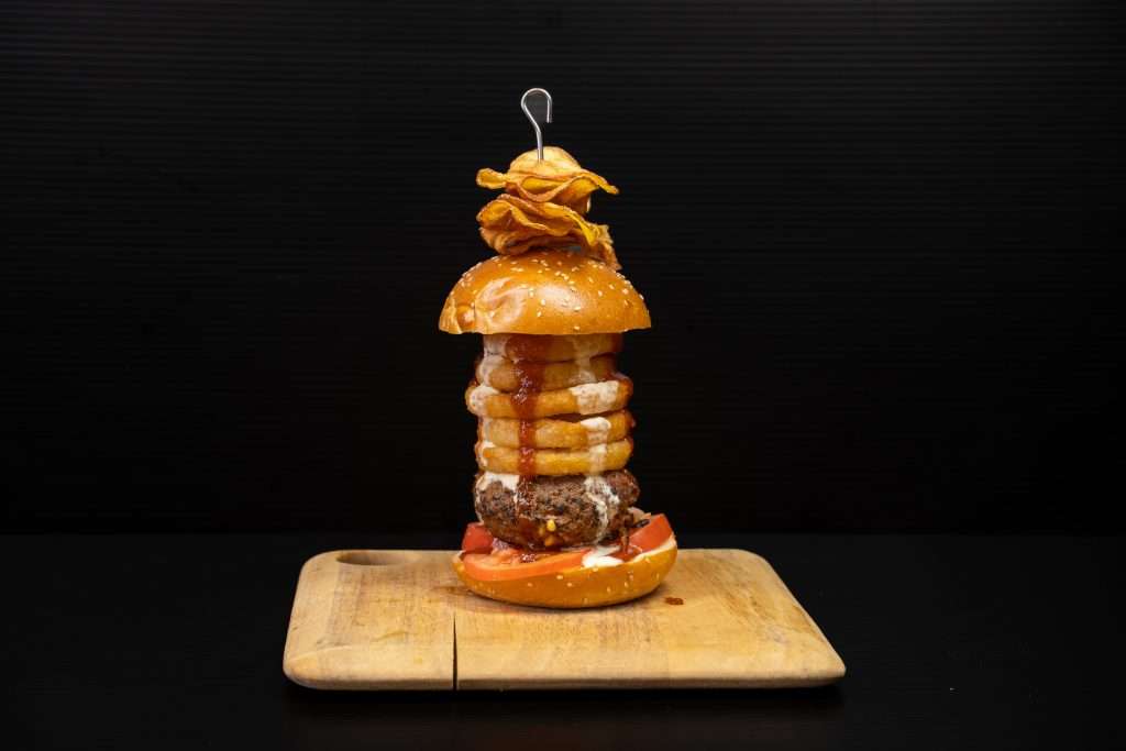 Juicy Lucy burger stacked with onion rings on a board