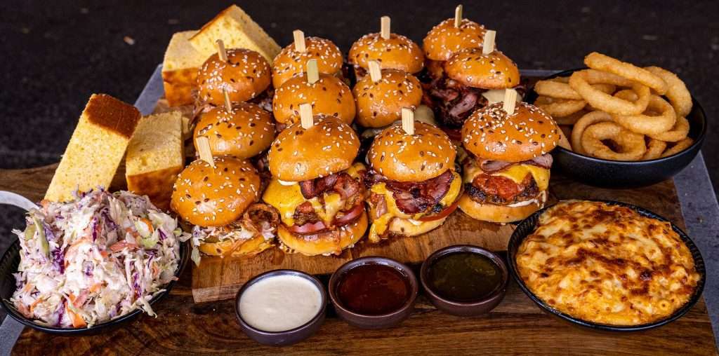 Catering board of sliders, onion rings, coleslaw, dips and cornbread