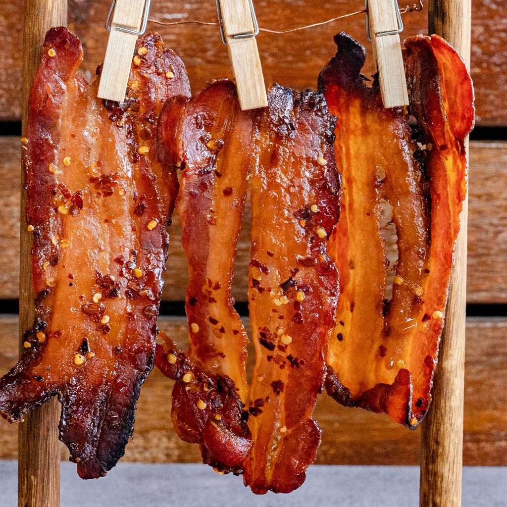Candy bacon strips hanging from wooden pegs