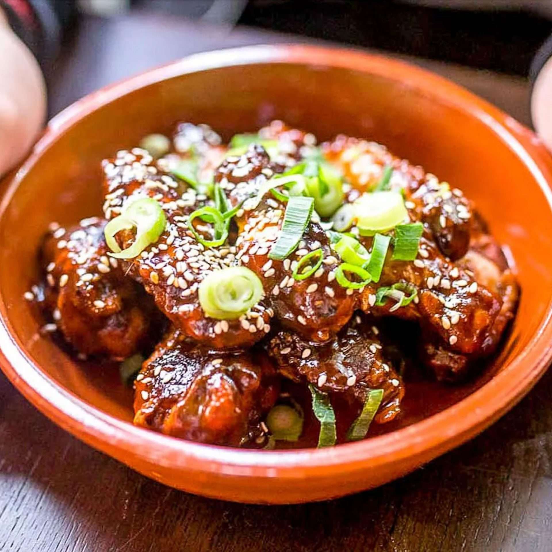 Oink Balls pork bites in a bowl, garnished with spring onion