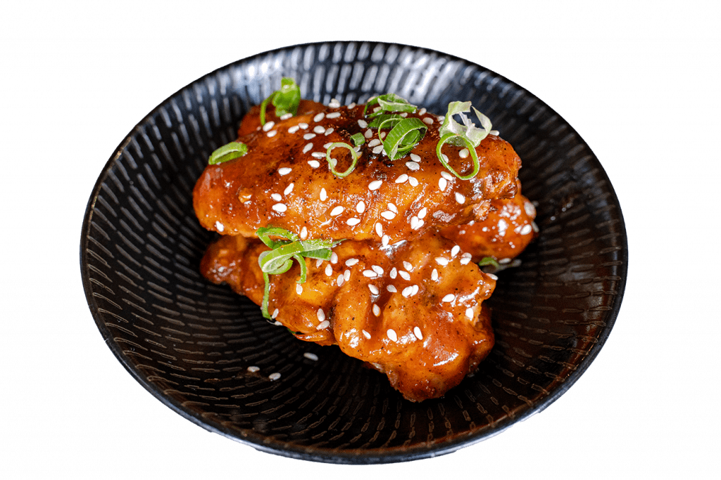 Glazed chicken wings topped with sesame seeds and spring onion
