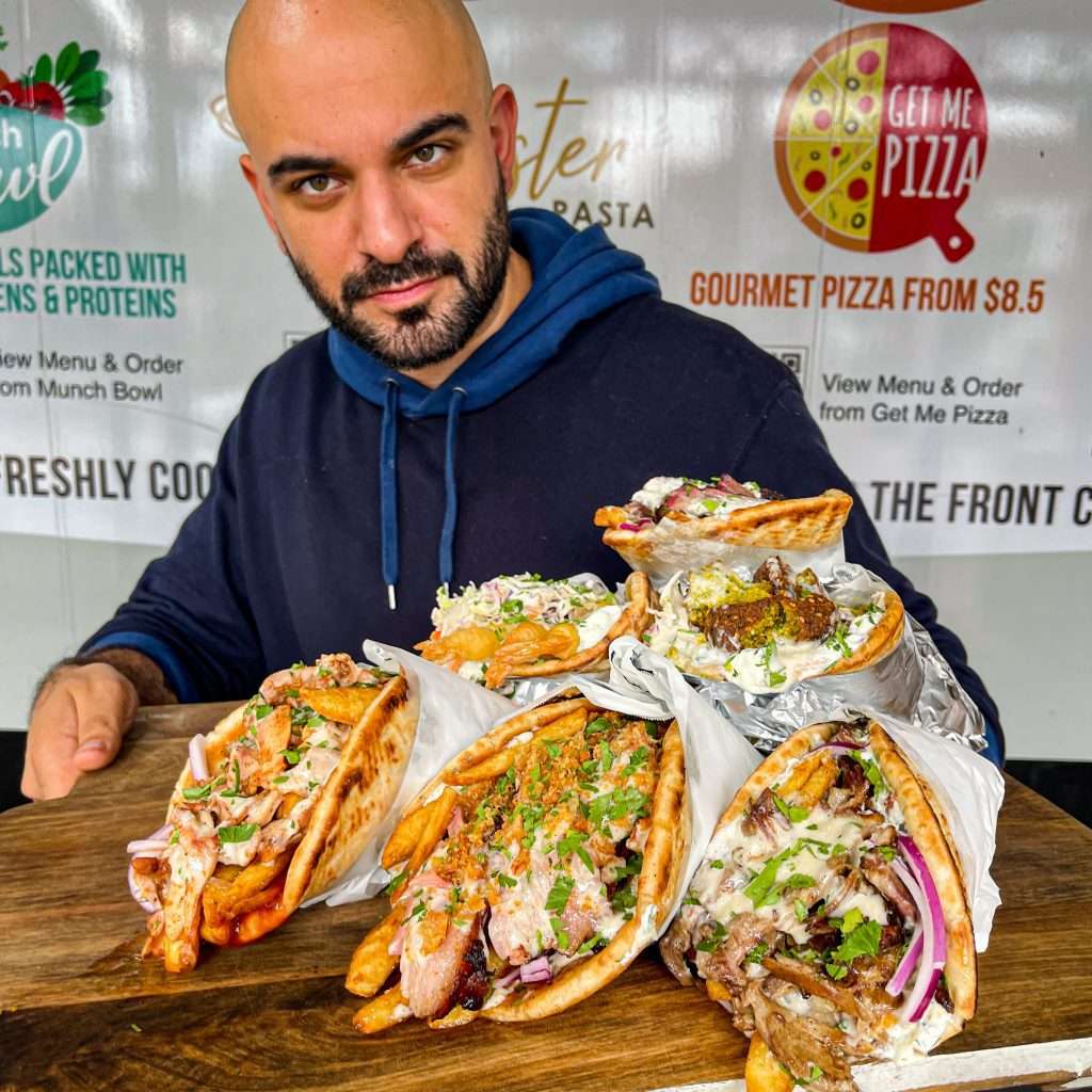 Person presenting a table of Skordo wraps and souvlaki