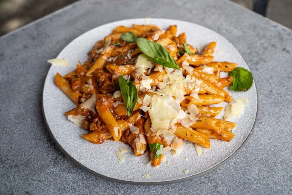 Penne pasta in tomato sauce topped with melted cheese and basil