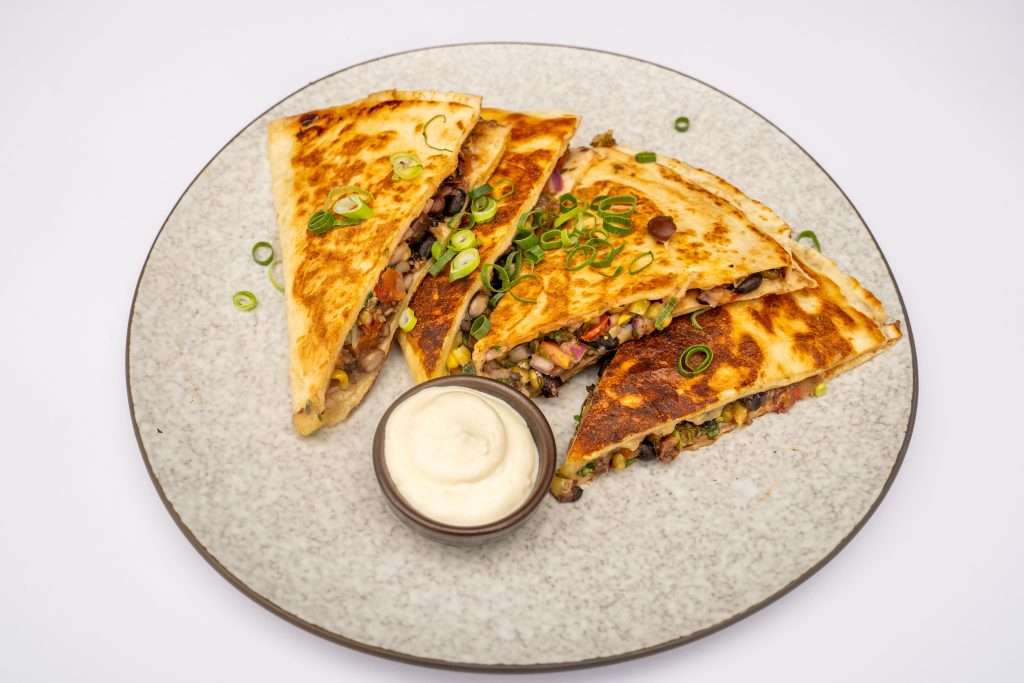 Quesadilla triangles with a sour cream dip on a plate