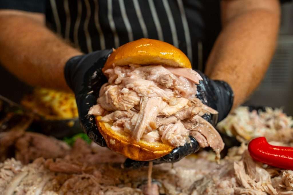 Pulled pork sandwich from the Whole Hog Degustation, hands pulling it apart