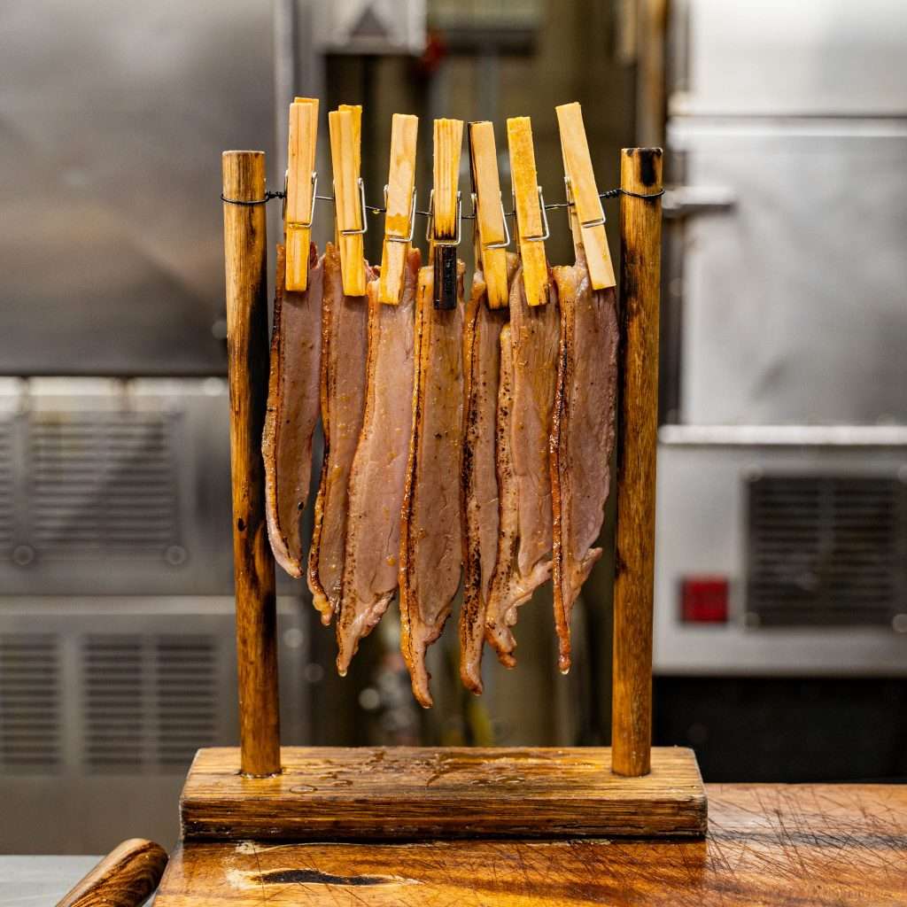 Strips of duck bacon hanging to cure in the kitchen