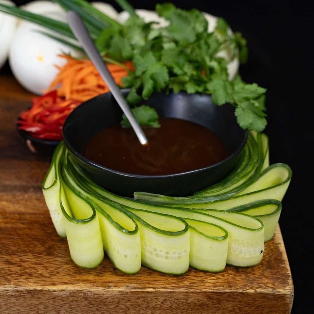 Dipping sauce bowl garnished with coriander and cucumber ribbons