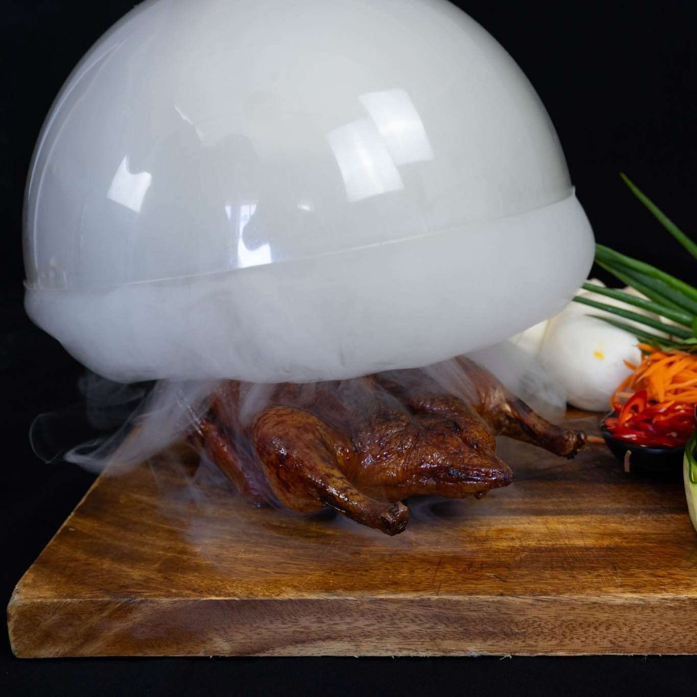 Smoked duck presented under a glass smoke dome on a board