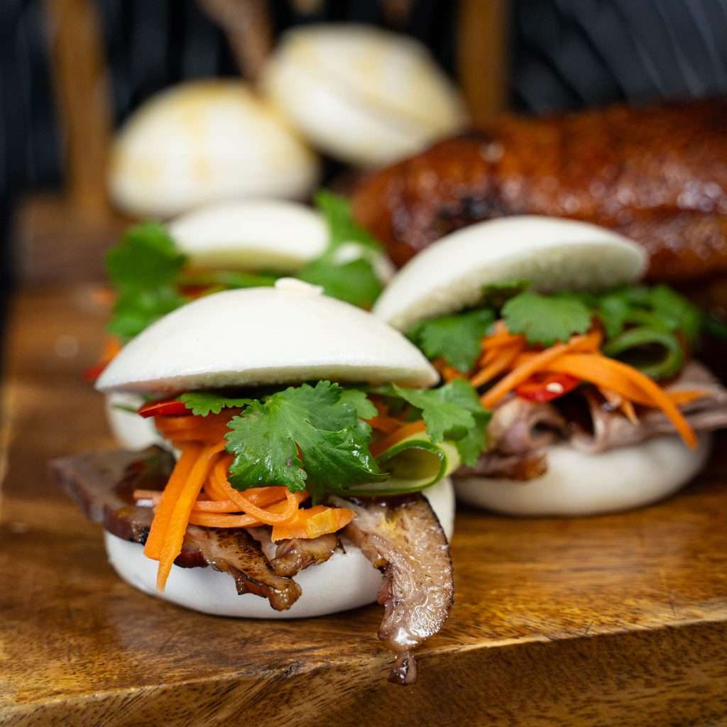 Steamed bao buns filled with pulled duck and pickled carrot