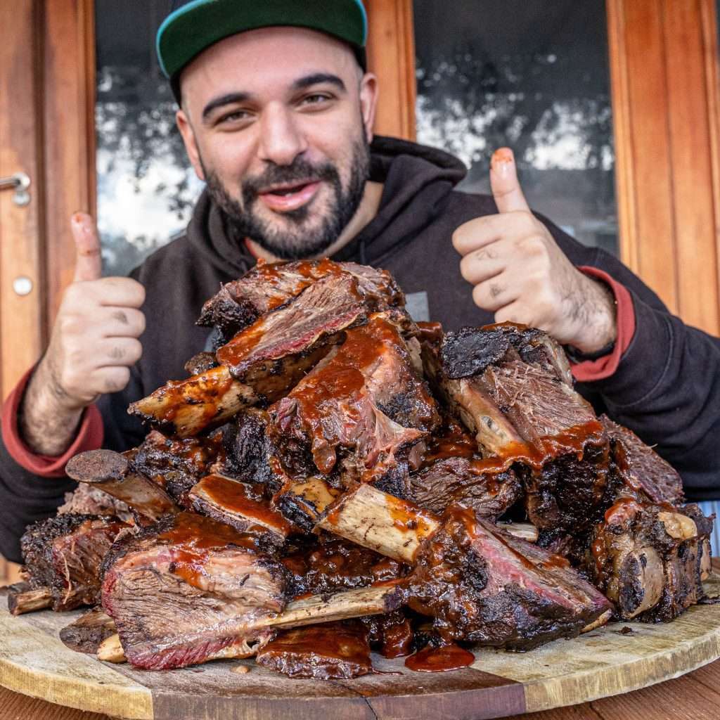 Guest giving a thumbs up behind a pile of smoked beef ribs
