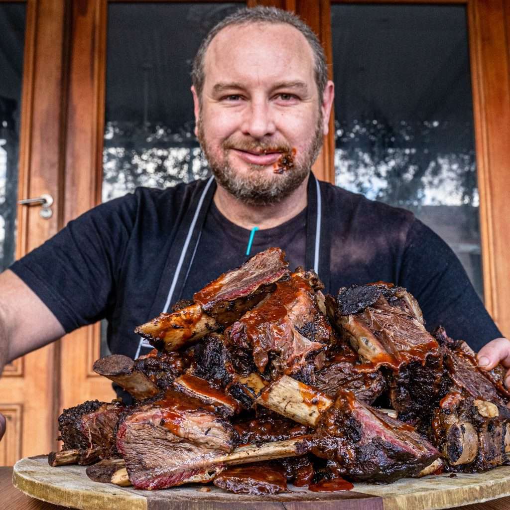 Guest smiling behind a large pile of smoked beef ribs