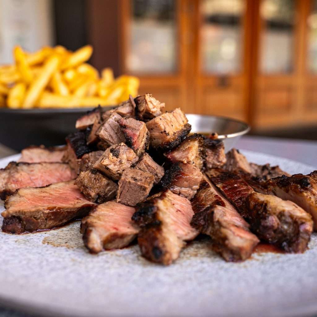 Steak bites and fries on a plate at an outdoor table