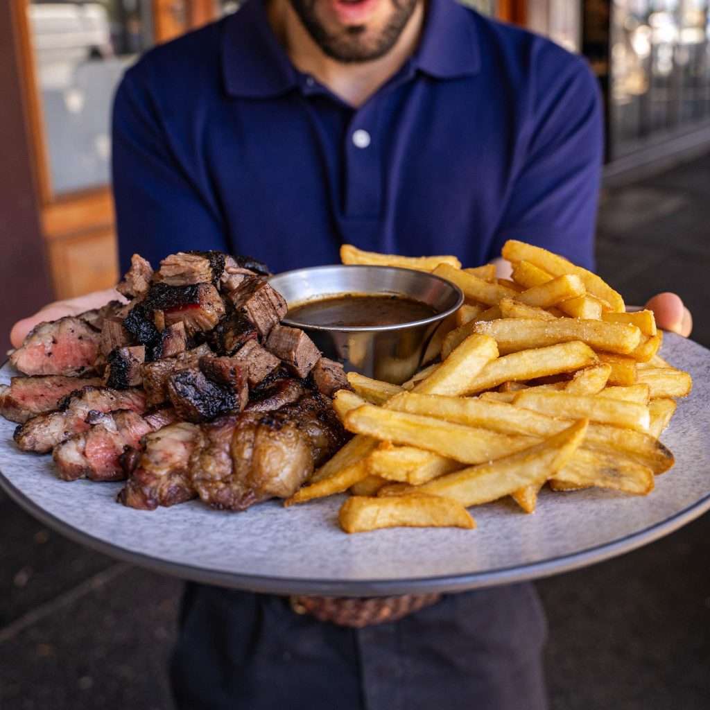 Person holding a plate of steak bites and fries with gravy