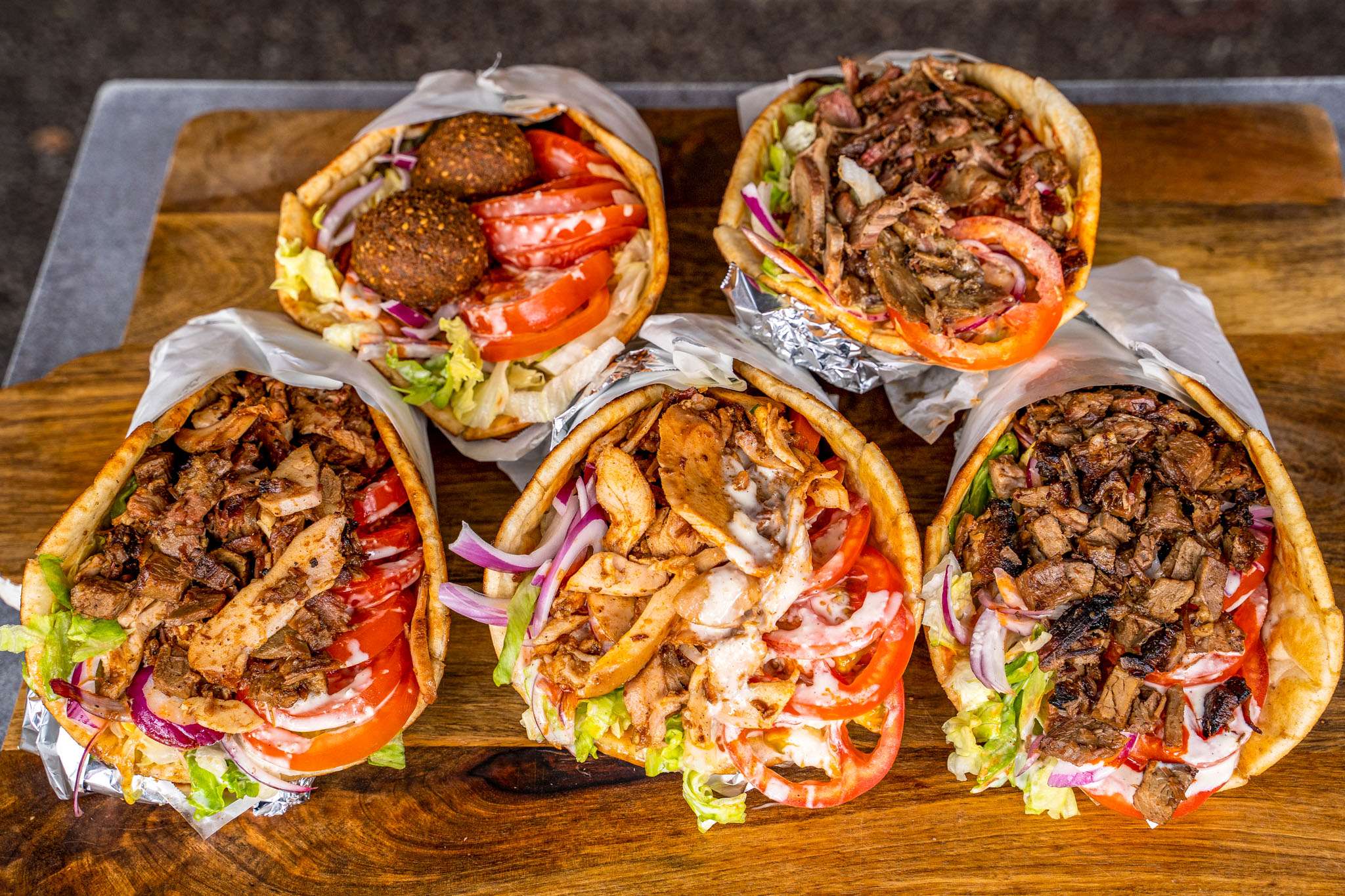 Assorted kebab wraps with falafel, salad and meat on a board