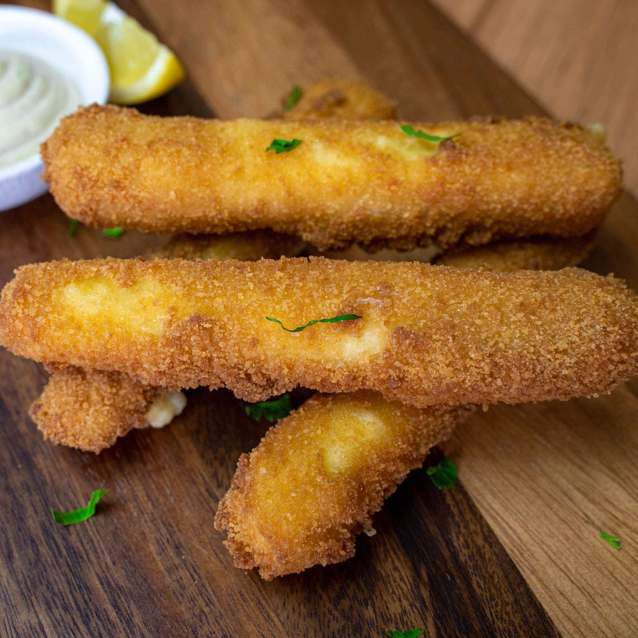 Crumbed fried cheese sticks with a dipping sauce and lemon