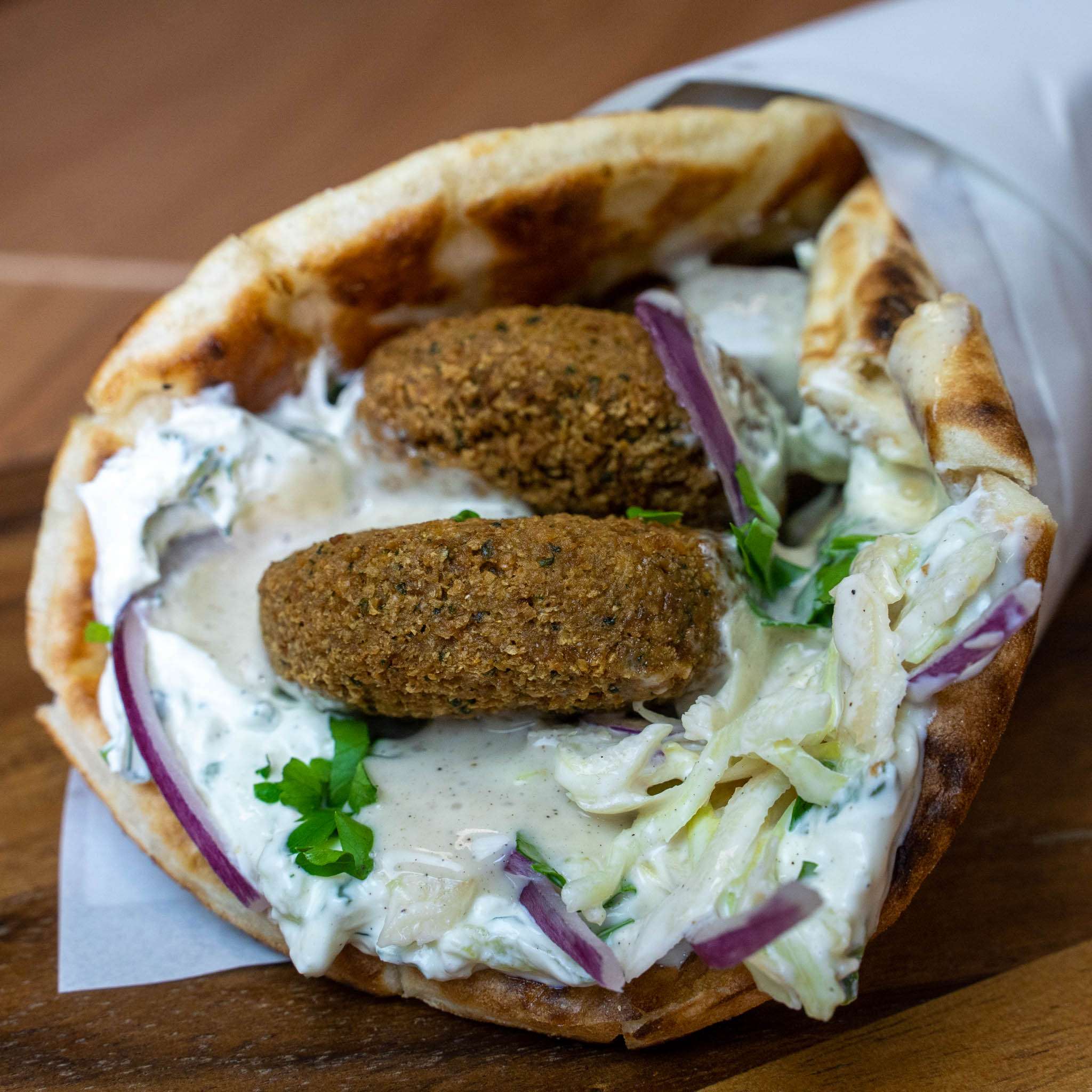 Falafel pita wrap with tzatziki, cabbage and red onion