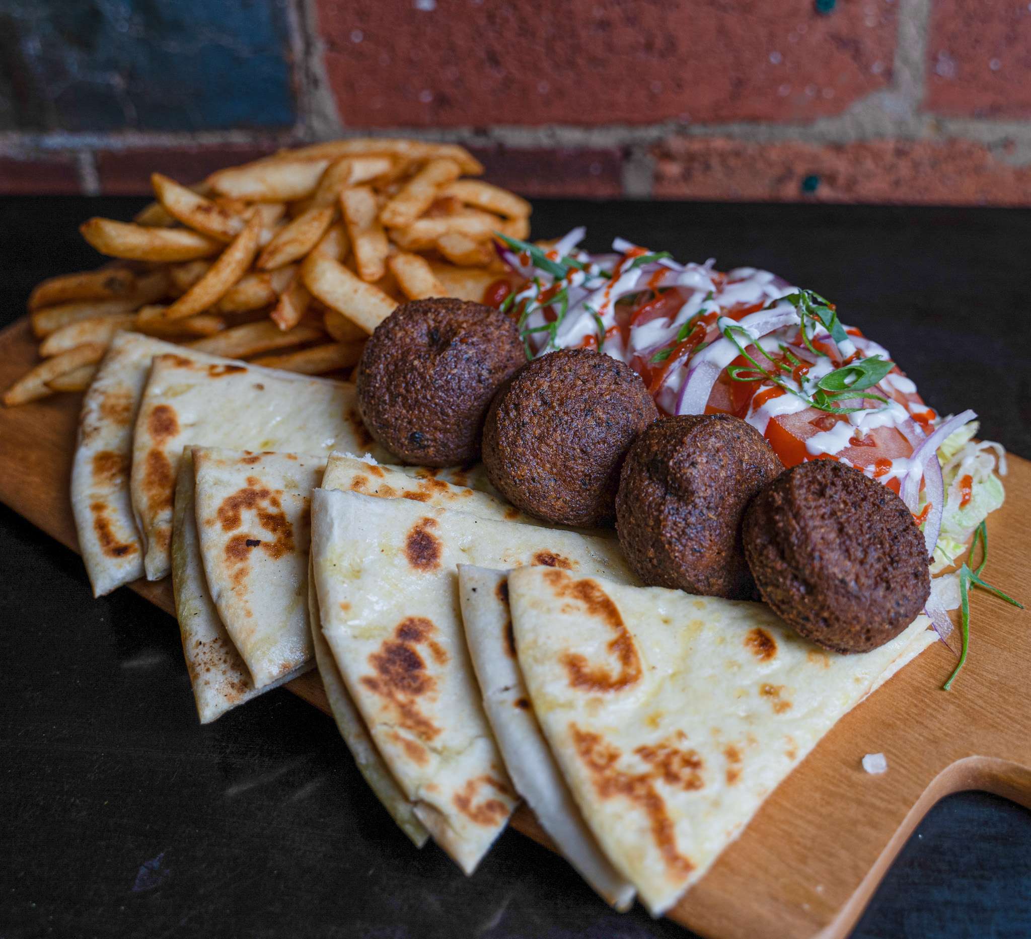 Falafel grill platter with pita bread and chips on a board