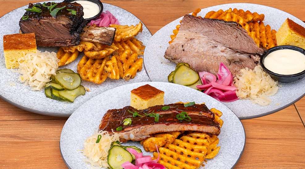 Plated brisket, ribs, waffle fries, cornbread and pickles