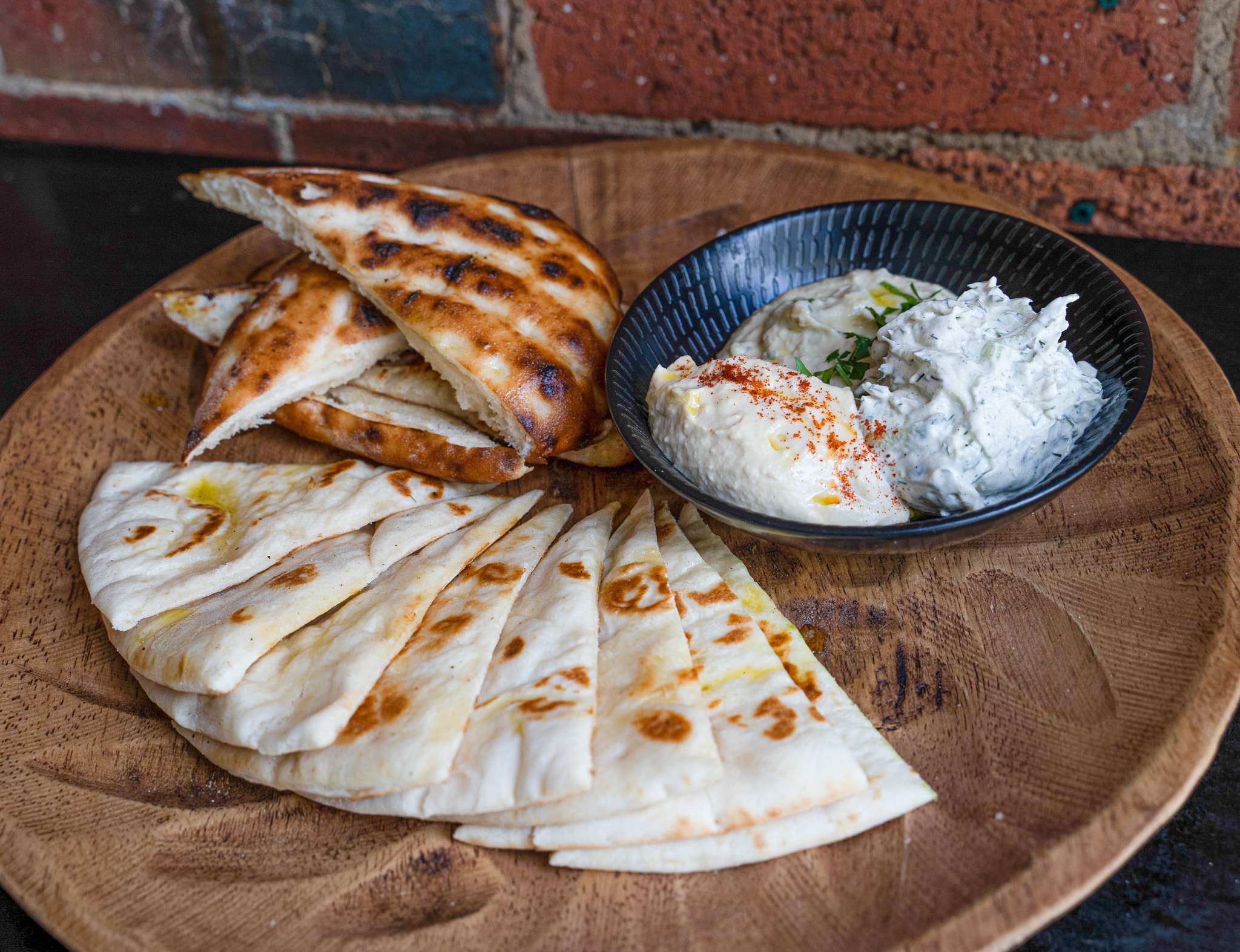 Toasted pita bread wedges served with a dip on a wooden board