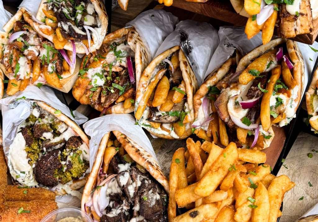 Overhead view of assorted souvlaki wraps and chips for catering