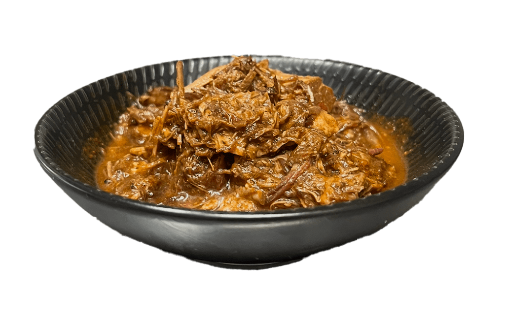 Bowl of birria-style shredded brisket in red chilli sauce