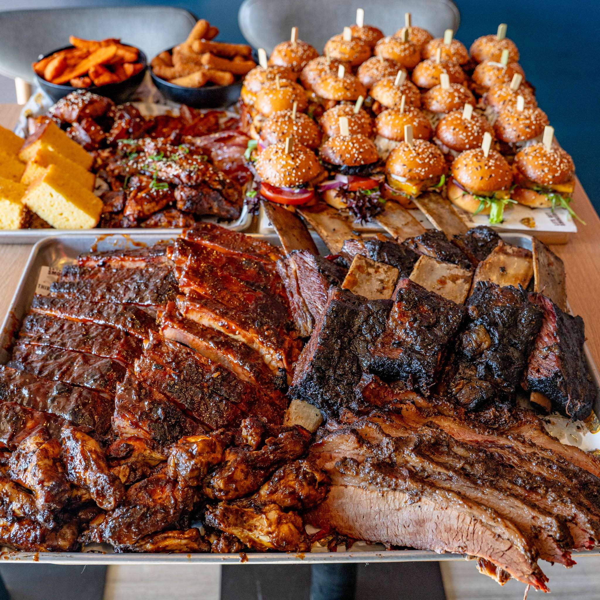 Catering spread of ribs, brisket, sliders, waffle fries and cornbread