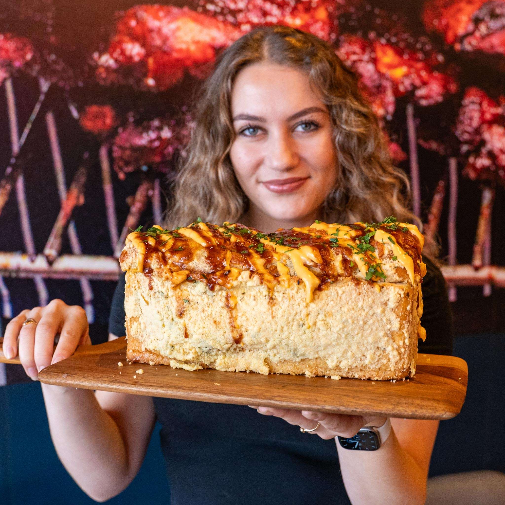 Person holding a large BBQ Brick loaf with sauce drizzle