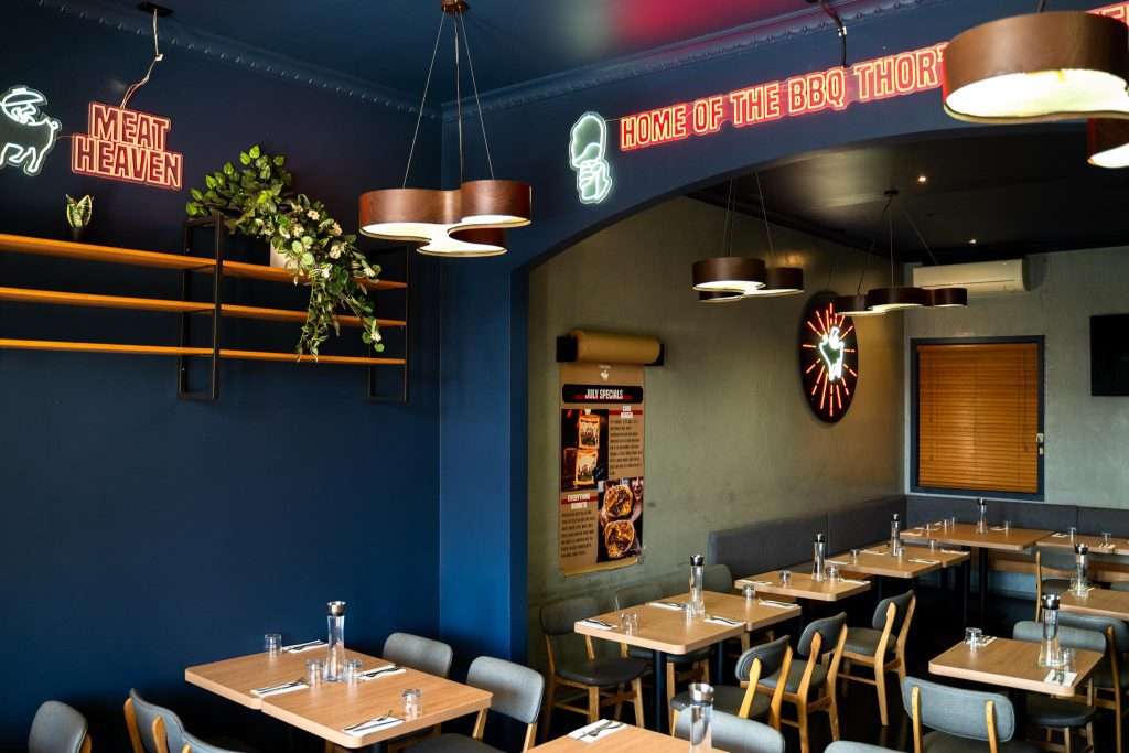 Dining room interior with neon 'Meat Heaven' signage at Third Wave BBQ