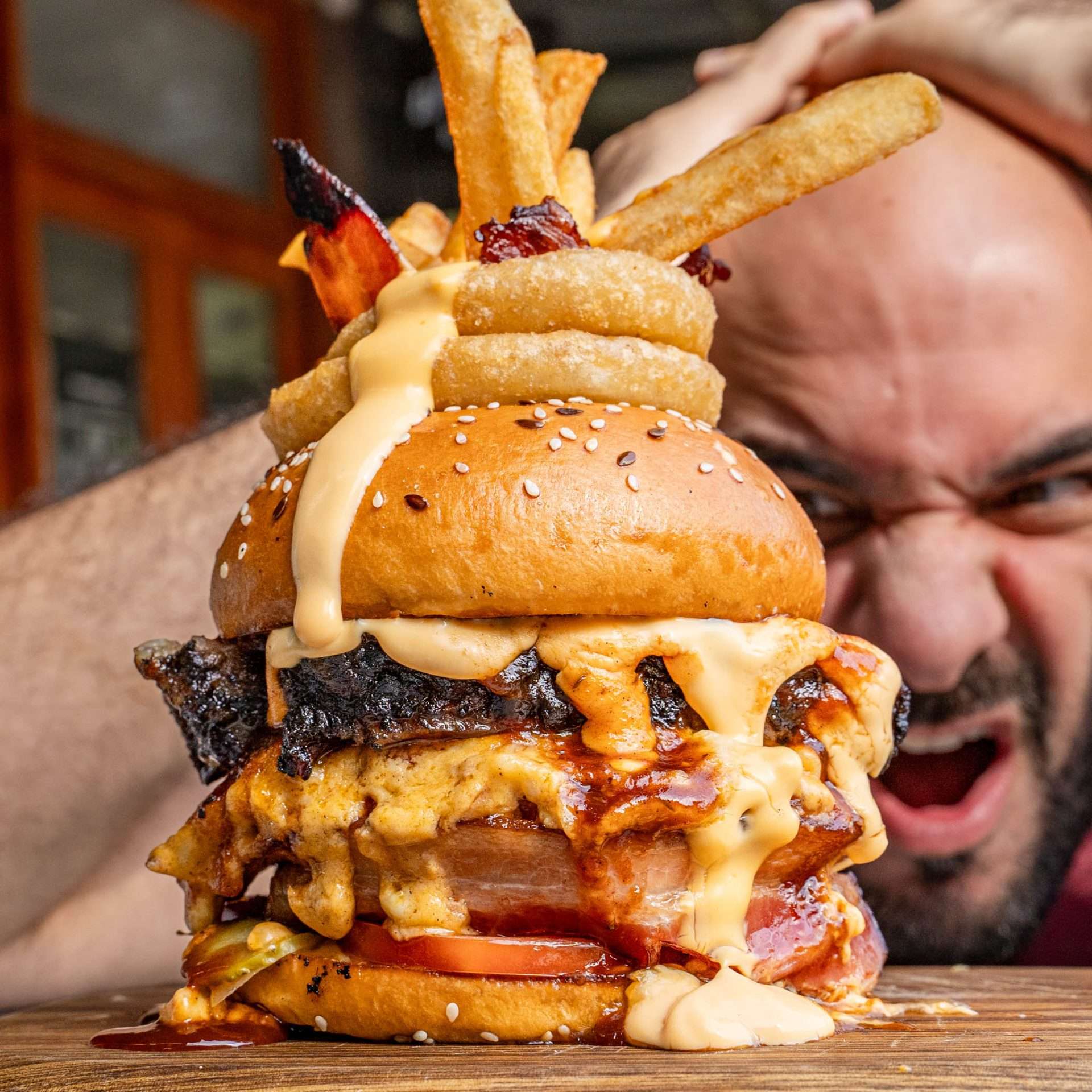 Mac Bomb On Steroids burger stacked with cheese and onion rings