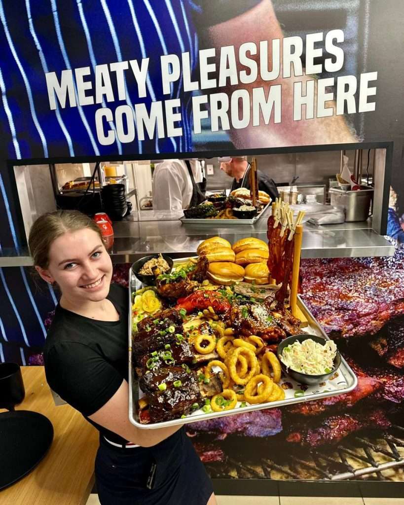 Staff member holding a large BBQ platter at Third Wave BBQ Moorabbin