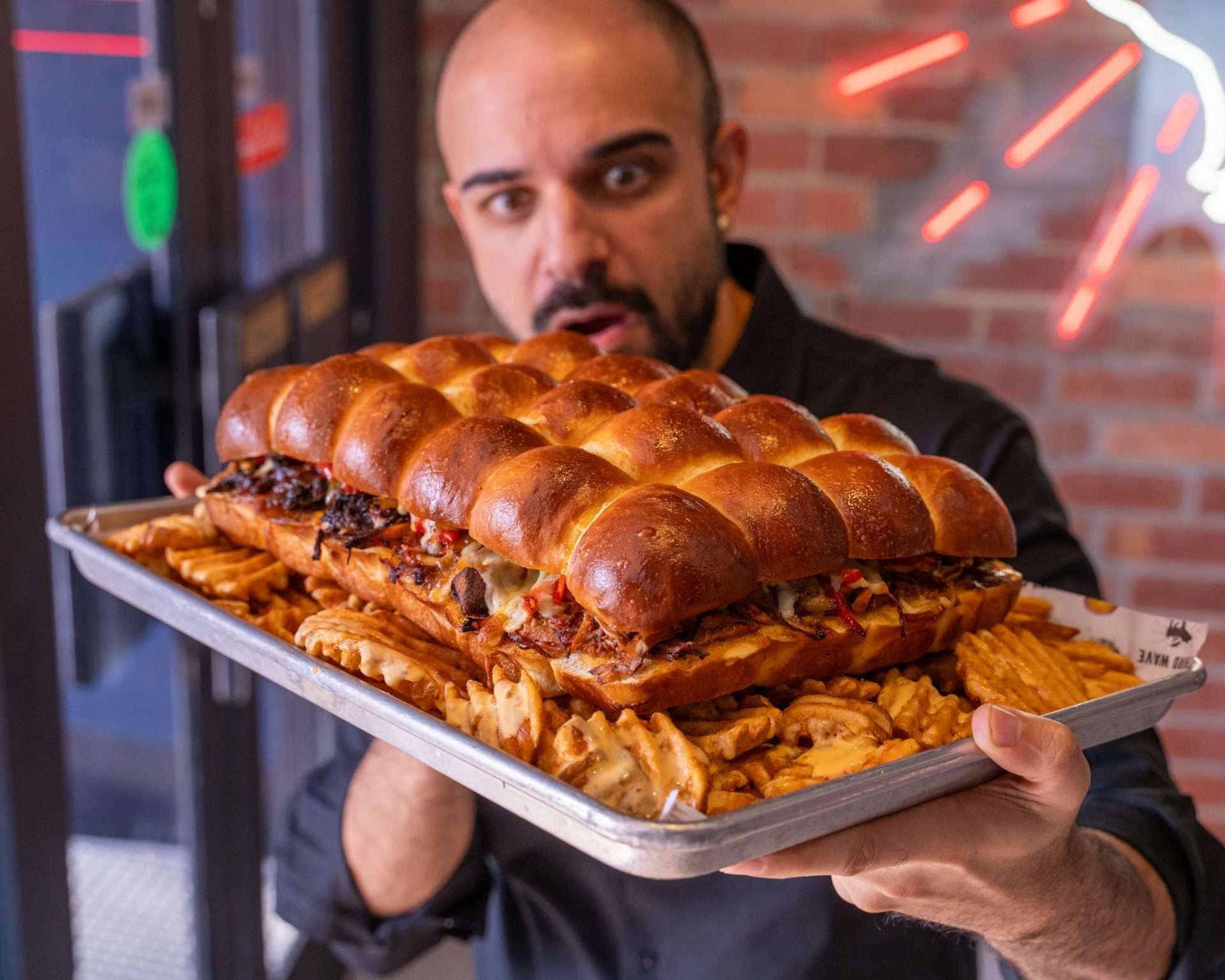 Guest holding a loaded Slider Slab tray of sliders and fries
