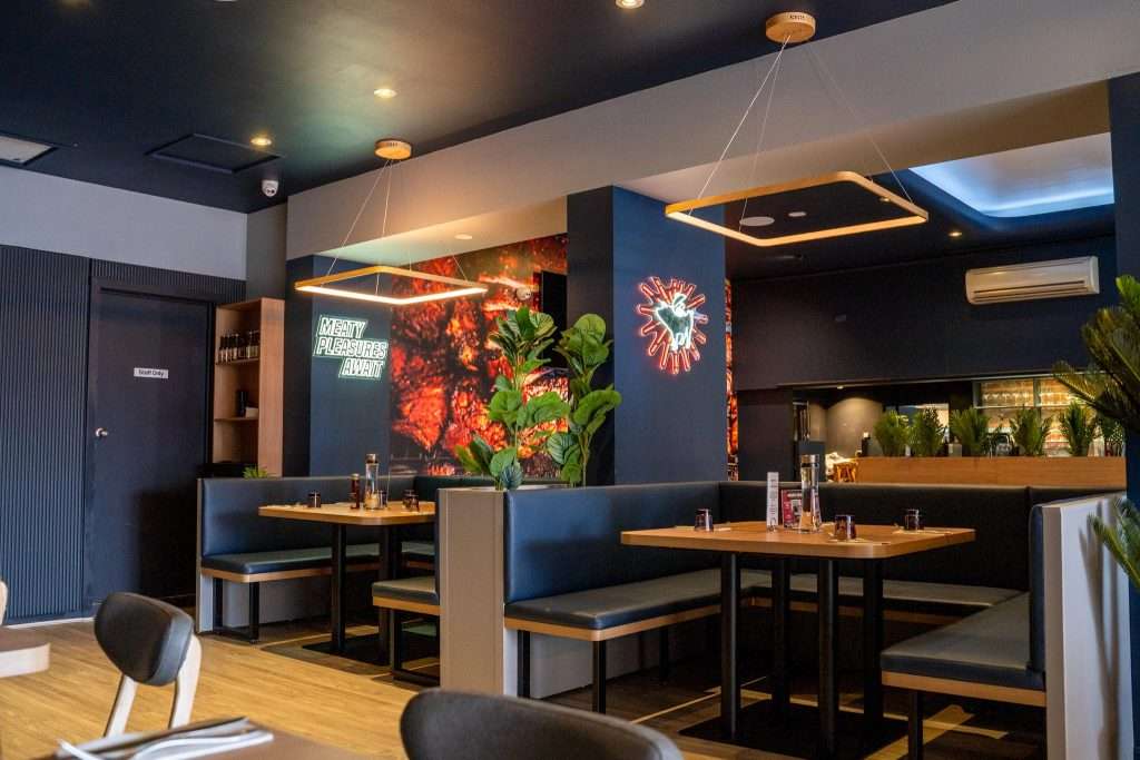 Dining booths and neon pig logo at Third Wave BBQ Hawthorn East