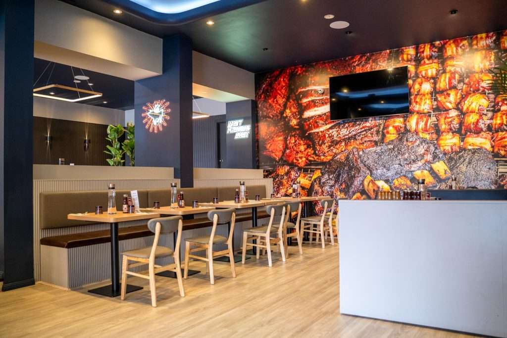 Communal dining table beneath a smoked-meats mural at Third Wave BBQ Hawthorn East