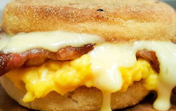Bacon and egg breakfast muffin with melted cheese oozing out