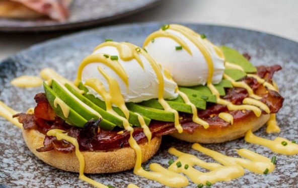 Poached eggs, avocado and candied bacon on toast with hollandaise drizzle