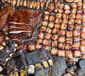 Smoked meats and bacon-wrapped bites laid out on a barbecue smoker grate